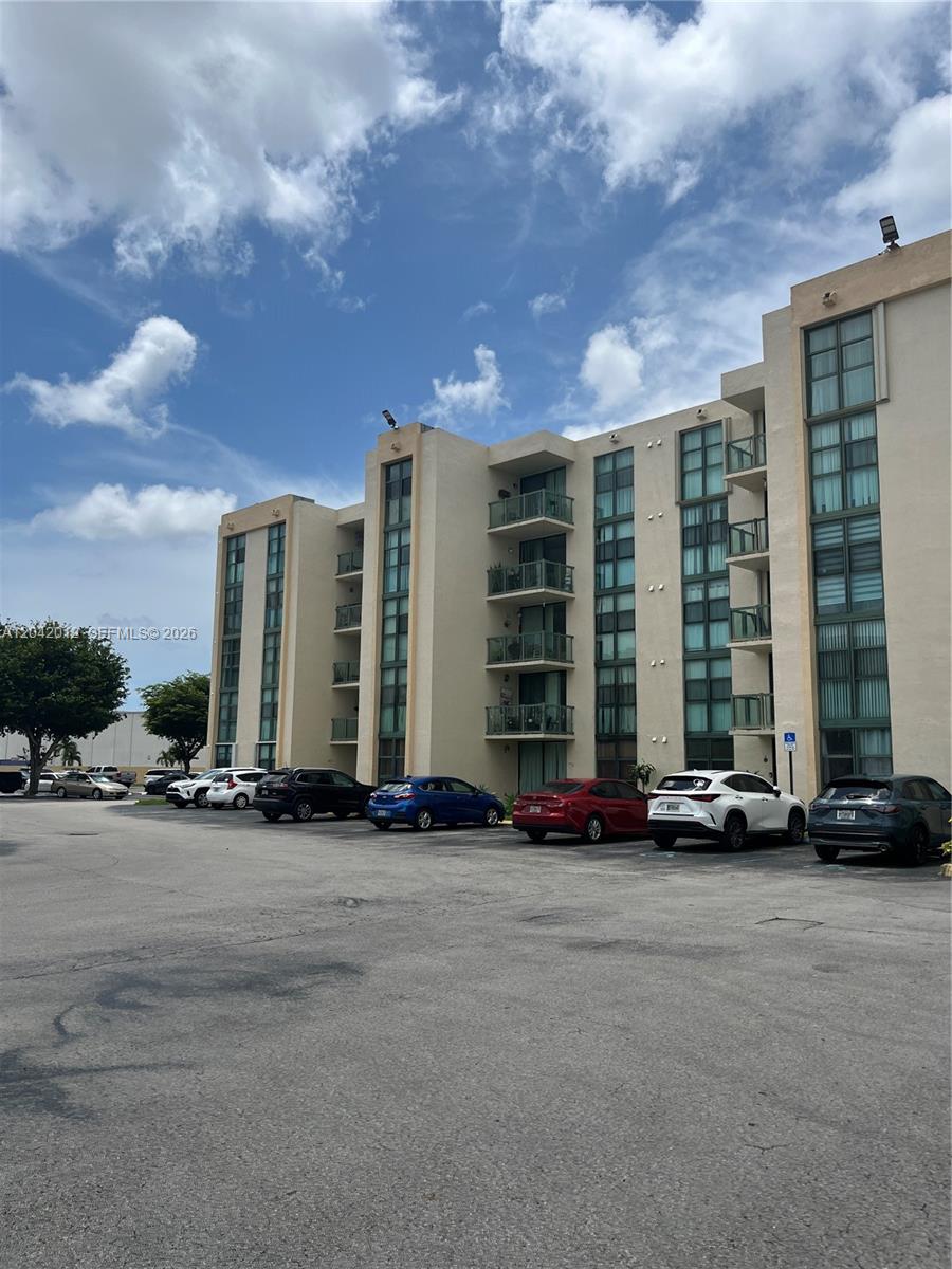 A multi-story apartment building with balconies stands behind a paved parking lot — 2055 SW 122nd Ave # 321, Miami FL 33175, MIAMI, FL