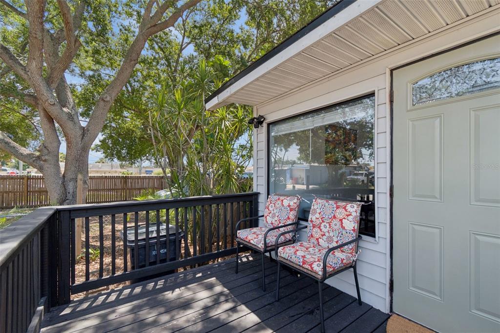 A wooden deck features two patterned chairs next to a light green door and window — 4924 45TH AVENUE N, ST PETERSBURG, FL