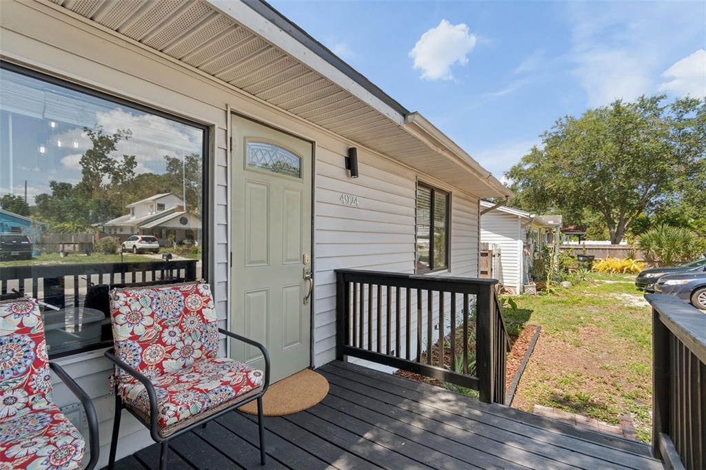 A wooden porch with two chairs leads to a light green front door of a house — 4924 45TH AVENUE N, ST PETERSBURG, FL