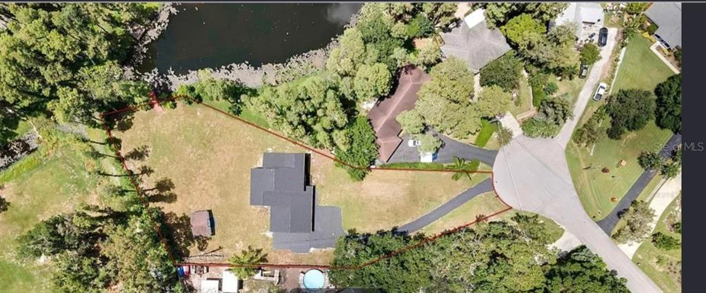 An aerial view shows a house on a large lot with a driveway and pond — 19003 CEDAR LANE, LUTZ, FL