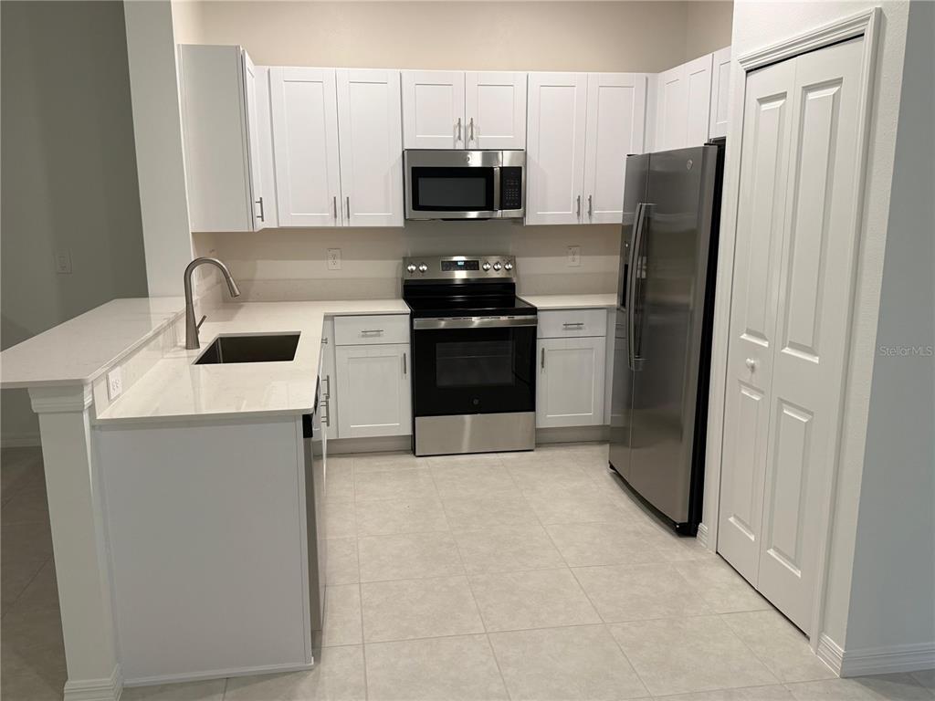 A kitchen features white cabinets, stainless steel appliances, and a quartz countertop with a sink — 10300 HONEY HAMMOCK WAY, SAN ANTONIO, FL