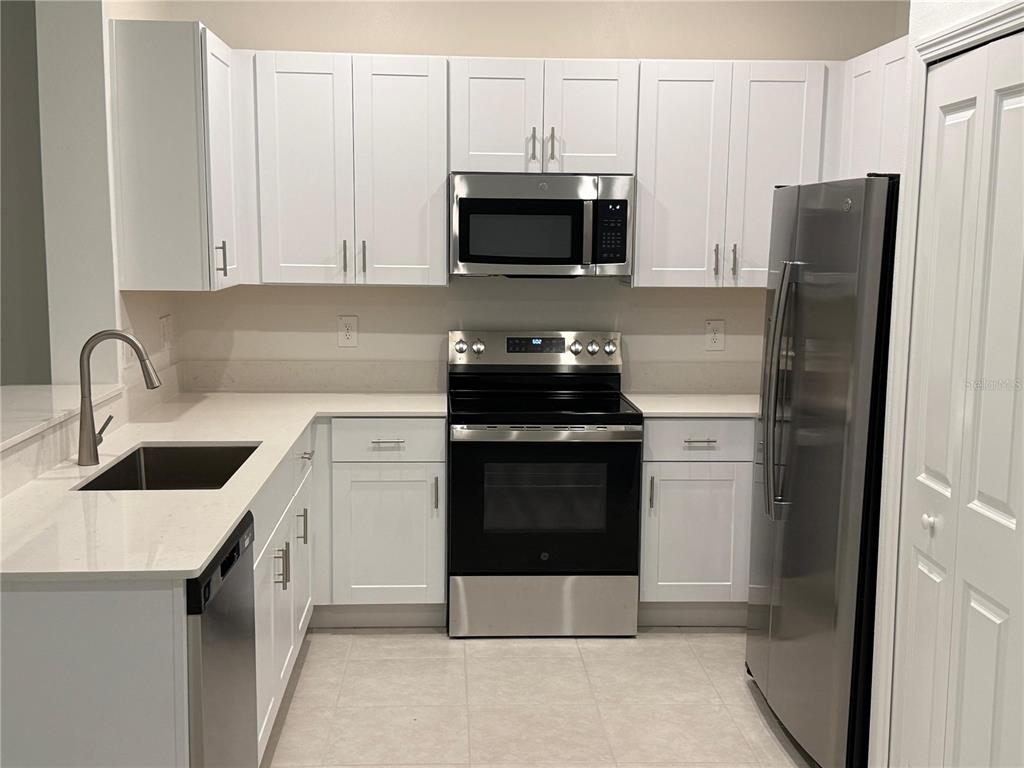 A kitchen features white cabinets, stainless steel appliances, and light-colored countertops — 10300 HONEY HAMMOCK WAY, SAN ANTONIO, FL