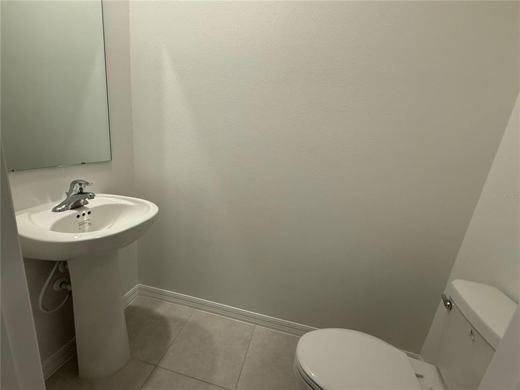 A small bathroom features a pedestal sink, a toilet, and a wall-mounted mirror — 10300 HONEY HAMMOCK WAY, SAN ANTONIO, FL