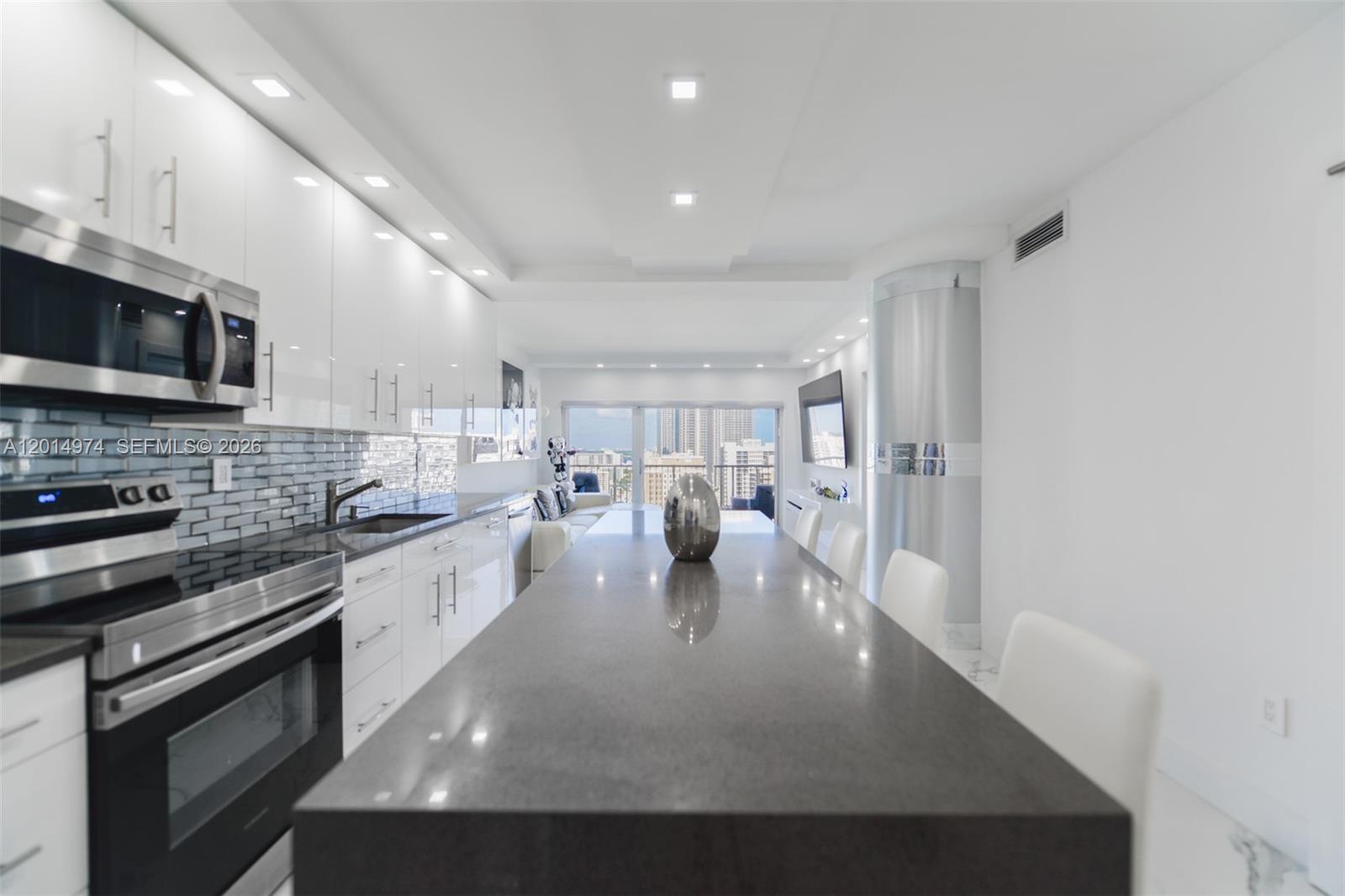 A modern kitchen features white cabinets, a dark gray island, and a view of buildings — 1980 S Ocean Dr, Hallandale Beach FL 33009, HALLANDALE BEACH, FL