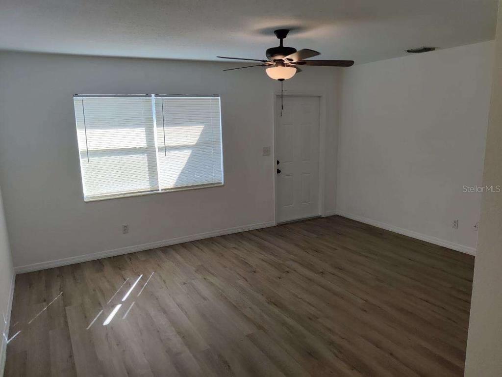 An empty room features light wood-look flooring, a ceiling fan, and a white door — 245 - 247 38TH AVENUE SE, ST PETERSBURG, FL