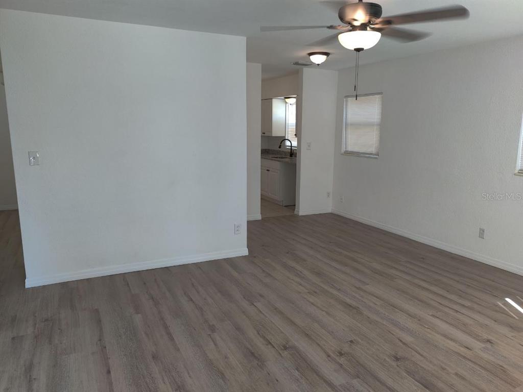 An interior view shows a living area with light wood-look flooring and a kitchen beyond — 245 - 247 38TH AVENUE SE, ST PETERSBURG, FL
