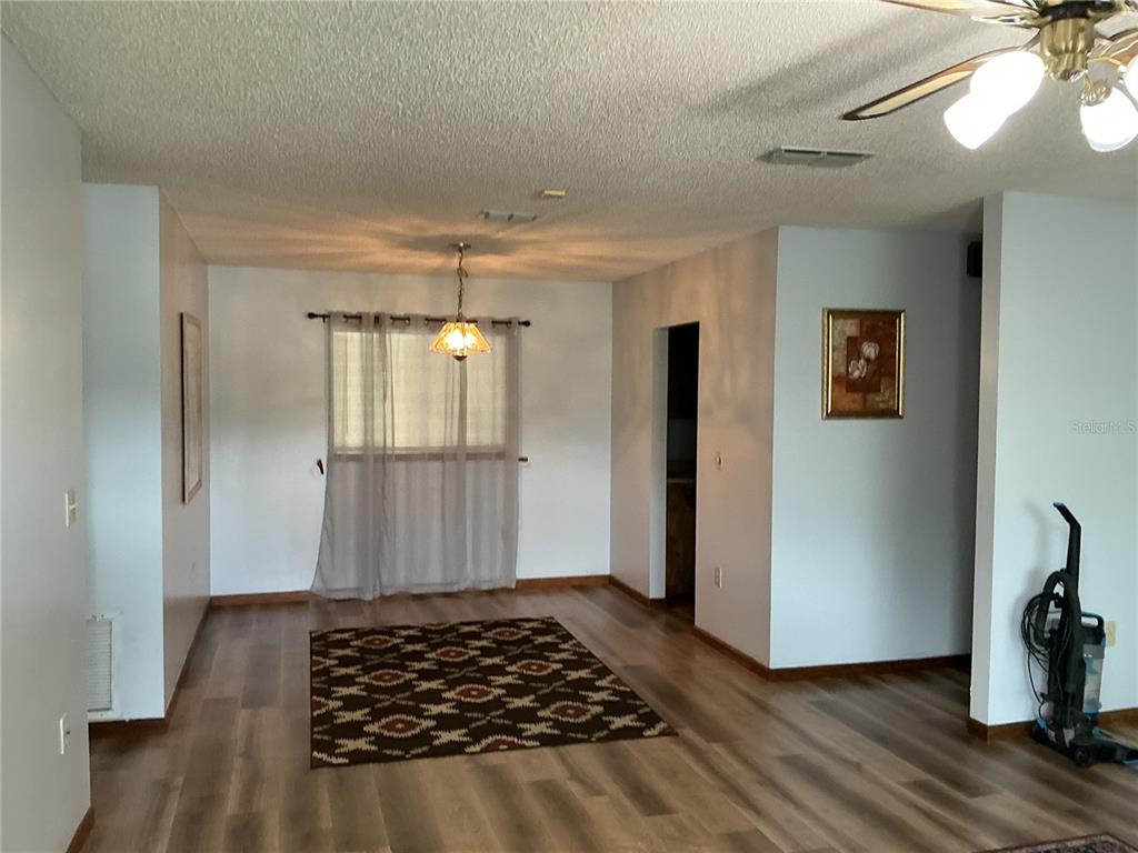 A dining area features light wood-look flooring, a patterned rug, and a central pendant light — 10415 SW 99TH AVENUE, OCALA, FL