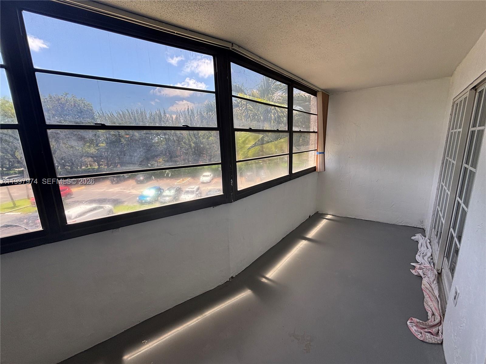 An enclosed balcony features gray painted flooring, white walls, and large horizontal sliding windows — 10854 N KENDALL DR # 316, Miami FL 33176, MIAMI, FL