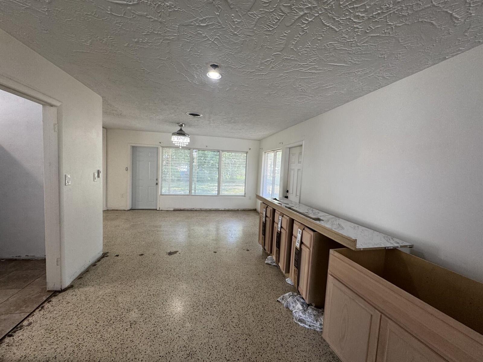 An unfinished kitchen area features light wood cabinets, a marble-look countertop, and speckled flooring — 2110 Cortez Boulevard, Fort Pierce FL 34982, FORT PIERCE, FL