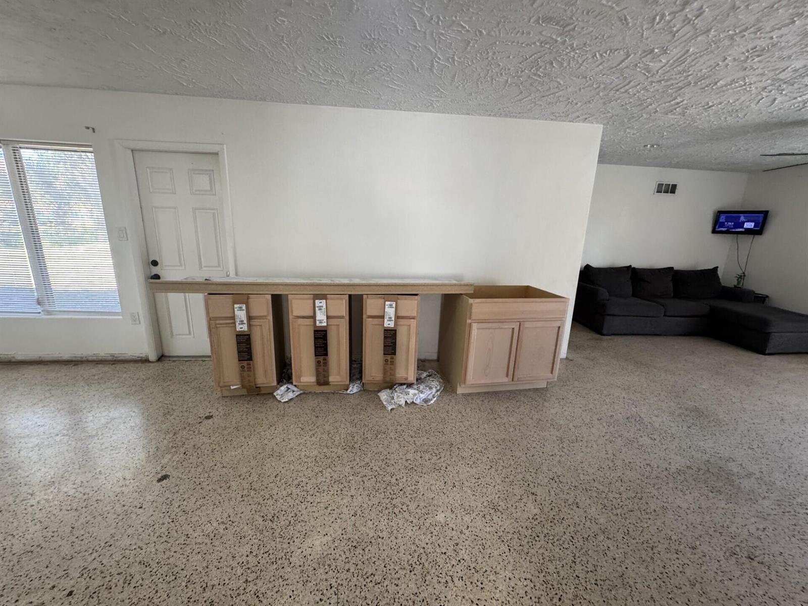 A room with a speckled concrete floor features four unfinished wooden cabinets topped with a countertop — 2110 Cortez Boulevard, Fort Pierce FL 34982, FORT PIERCE, FL