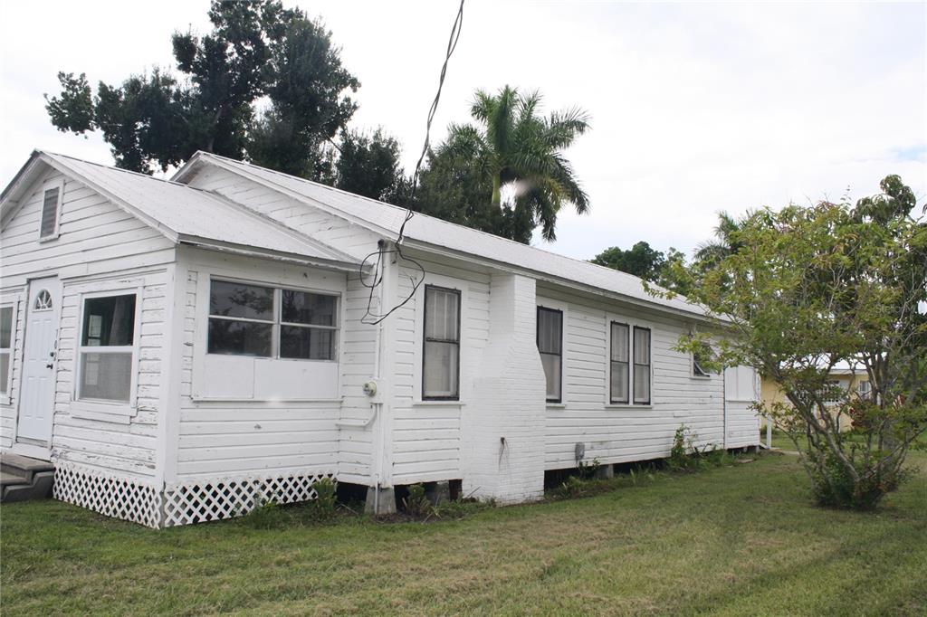 A white, single-story house with horizontal siding, a metal roof, and a lattice foundation — 702 W OLYMPIA AVENUE, PUNTA GORDA, FL