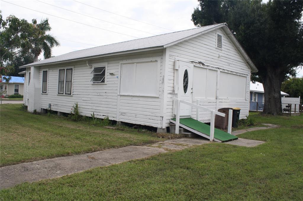 A white, single-story house with horizontal siding, a metal roof, and a green wheelchair ramp — 702 W OLYMPIA AVENUE, PUNTA GORDA, FL