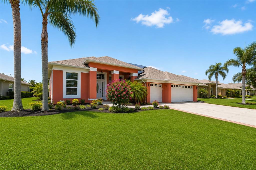 A single-story orange house with a two-car garage and palm trees on a sunny day — 5805 WEDGEFIELD DRIVE, ZEPHYRHILLS, FL