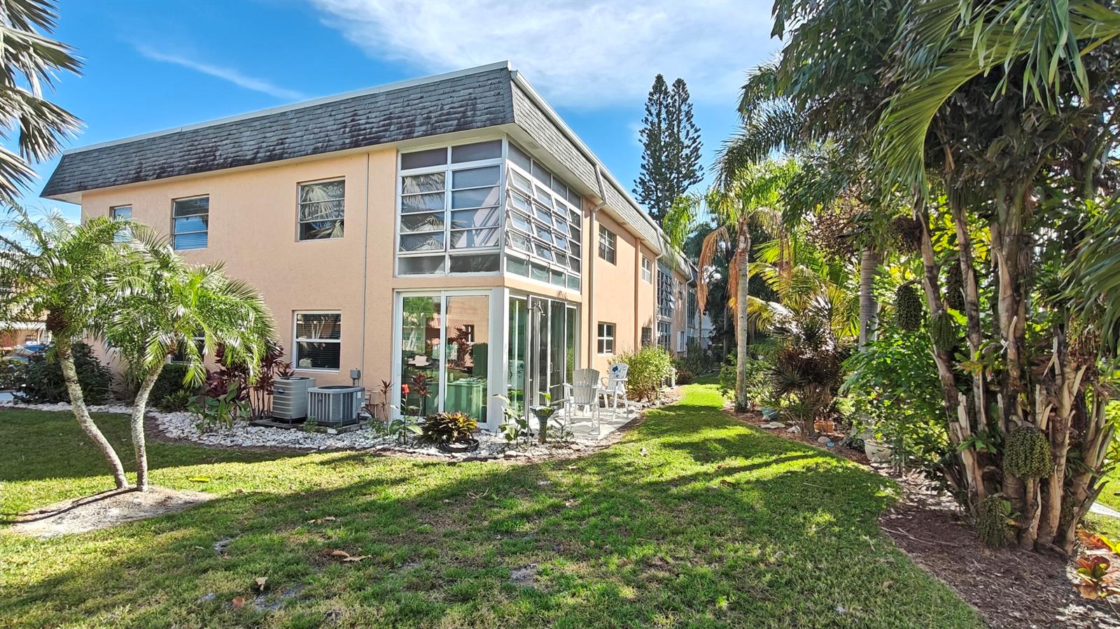 A two-story peach-colored apartment building with a glass-enclosed patio and surrounding tropical landscaping — 2950 SE Ocean Boulevard # 6, Stuart FL 34996, STUART, FL