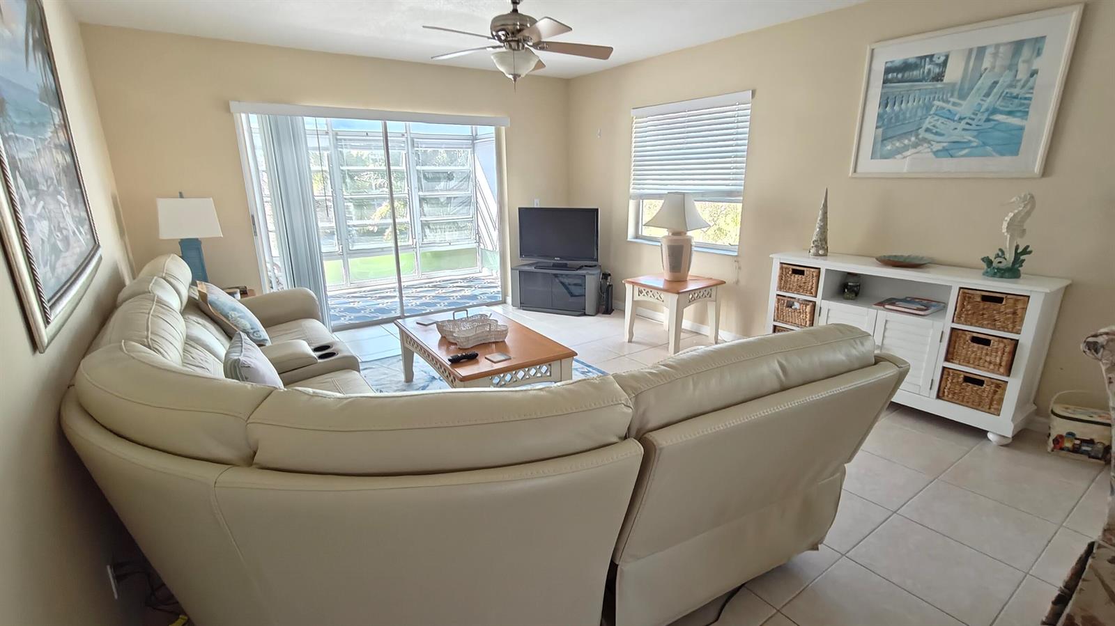 A living room features a large curved sofa, a coffee table, and a sliding glass door — 2950 SE Ocean Boulevard # 6, Stuart FL 34996, STUART, FL