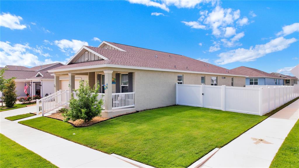 A single-story house with a front porch, tan stucco siding, and a white vinyl fence — 7185 SW 63RD STREET, OCALA, FL