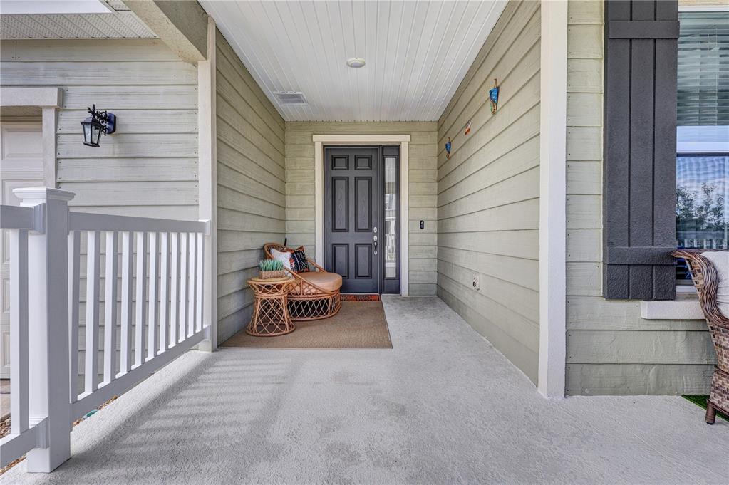 A covered front porch features light green siding, a dark door, and wicker furniture — 7185 SW 63RD STREET, OCALA, FL