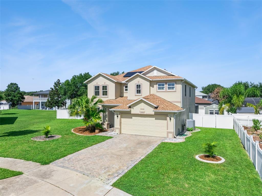 A two-story suburban house with a tan stucco exterior, shingled roof, and paved driveway — 15507 MARBLEHEAD WAY, CLERMONT, FL