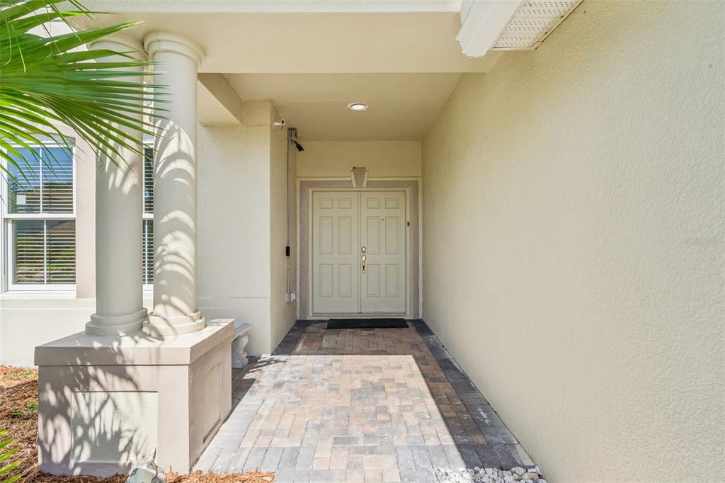 A covered entryway features a paved walkway leading to a double front door with columns — 15507 MARBLEHEAD WAY, CLERMONT, FL