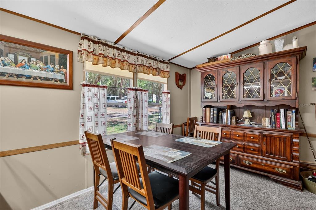 A dining room features a wooden table, chairs, and a large hutch against a wall — 1710 INDIAN TRAIL UNIT B, LEESBURG, FL