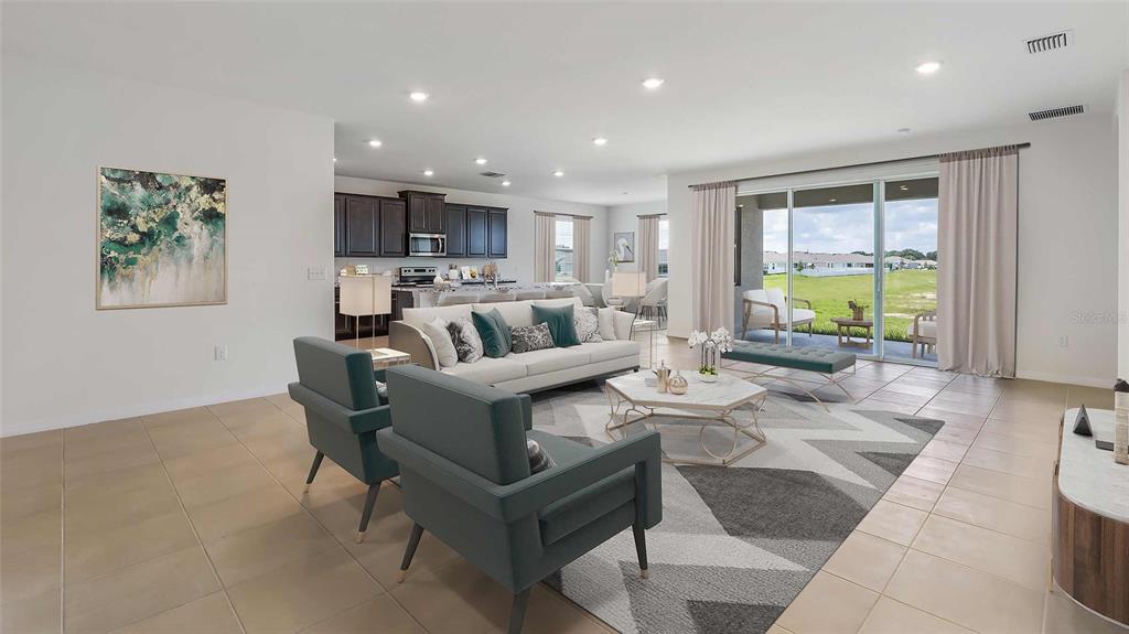 A modern kitchen features white cabinets, quartz countertops, a center island, and light wood flooring — 10421 WOODLAND GARDEN WAY, PARRISH, FL