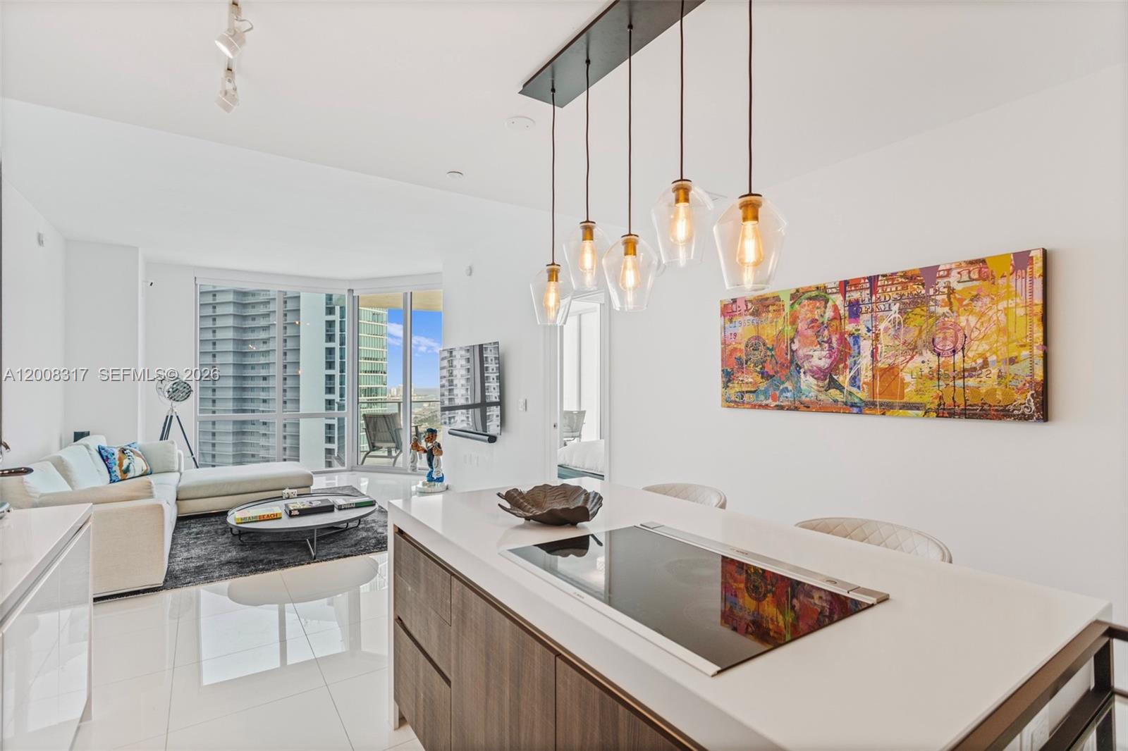 A modern kitchen island with a cooktop overlooks a living area with floor-to-ceiling windows — 851 NE 1st Ave # 3707, Miami FL 33132, MIAMI, FL