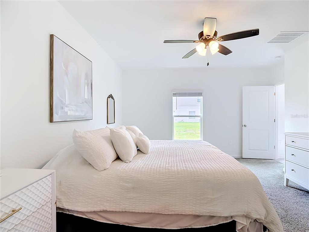 A bedroom features a bed with white bedding, a ceiling fan, and white furniture — 526 HATTERAS ROAD, DAVENPORT, FL