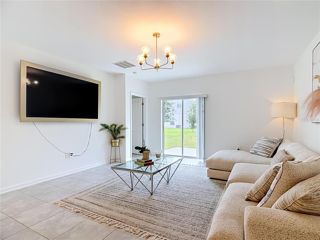 A living room features a wall-mounted television, a glass coffee table, and a sectional sofa — 526 HATTERAS ROAD, DAVENPORT, FL