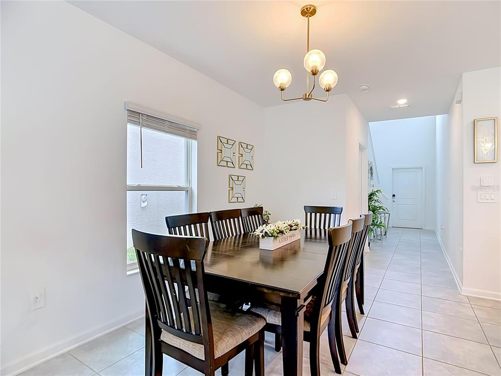 A dining room features a dark wood table, six chairs, and a modern light fixture — 526 HATTERAS ROAD, DAVENPORT, FL