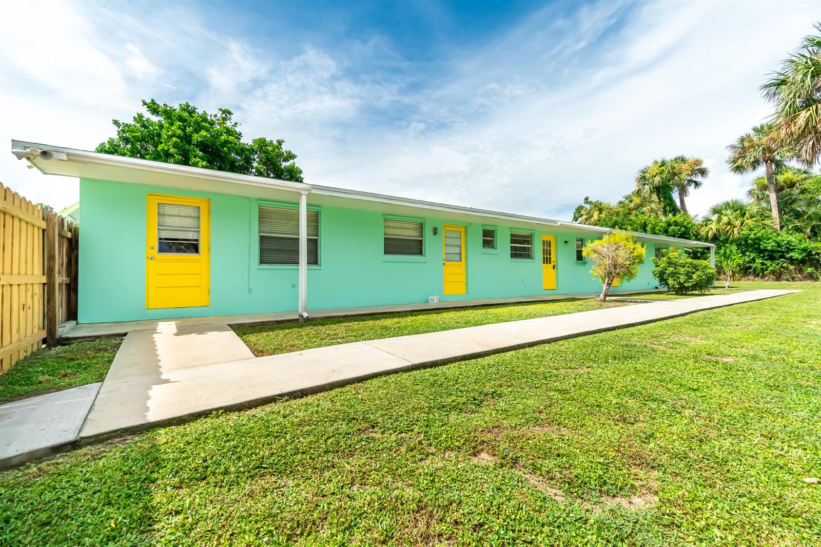 A single-story, mint-green apartment building with yellow doors and a concrete walkway — 2546 NE Hickory Avenue, Jensen Beach FL 34957, JENSEN BEACH, FL
