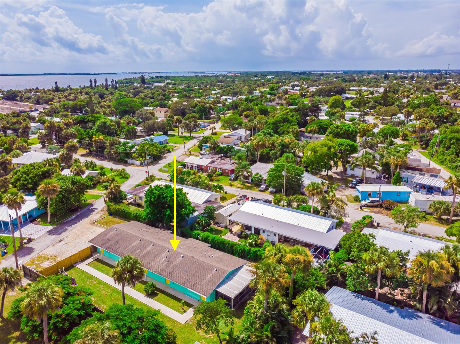 An aerial view shows a teal-colored house with a brown roof surrounded by lush vegetation — 2546 NE Hickory Avenue, Jensen Beach FL 34957, JENSEN BEACH, FL