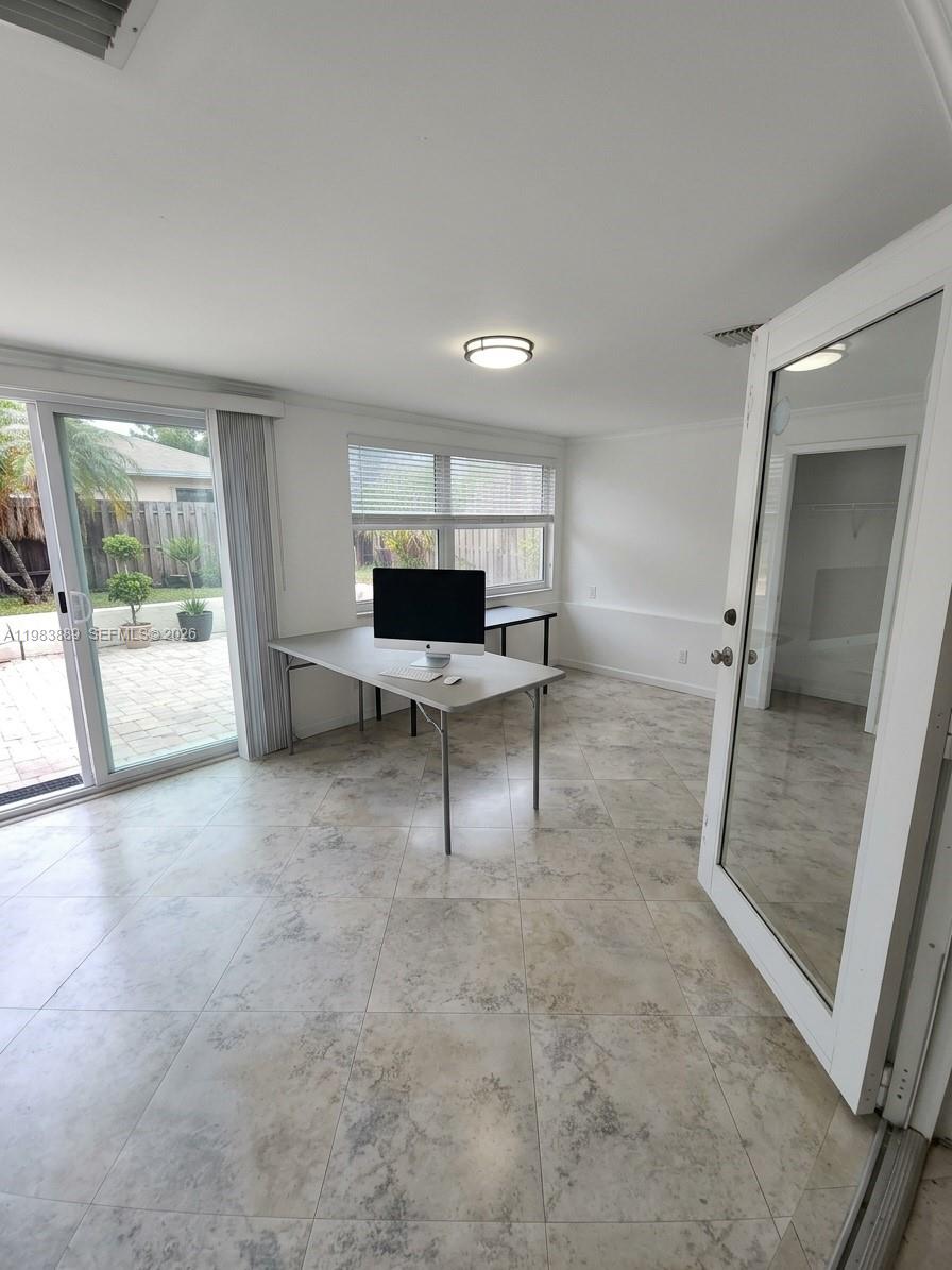 A bright office room features tile flooring, a desk with a computer, and sliding glass doors — 804 NE 2nd St, Hallandale Beach FL 33009, HALLANDALE BEACH, FL
