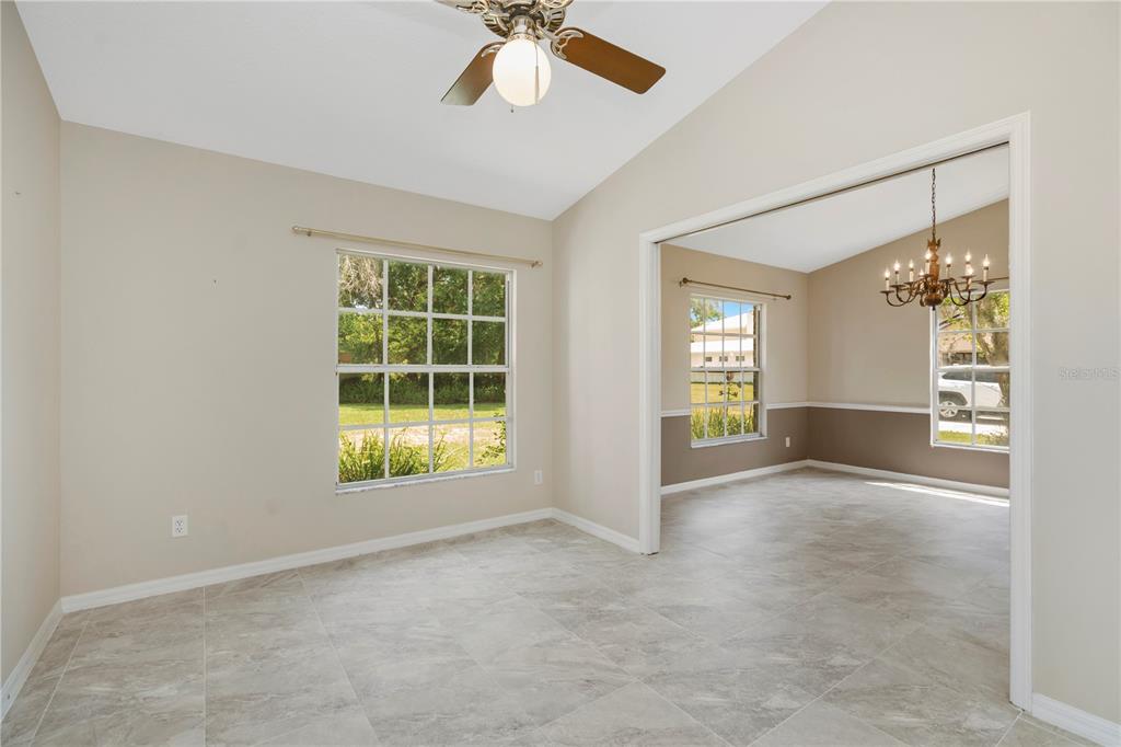 A bright dining area with tile floors leads into a living room with a chandelier — 785 DUQUE ROAD, LUTZ, FL