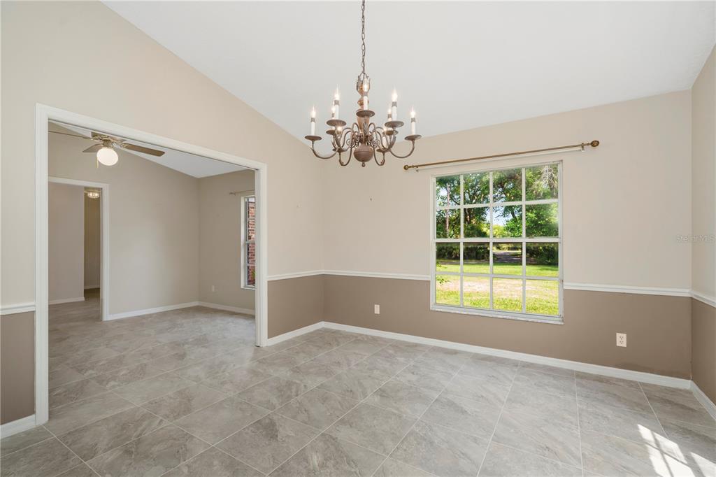 A dining room with tile flooring, a chandelier, and two-toned walls with chair rail molding — 785 DUQUE ROAD, LUTZ, FL