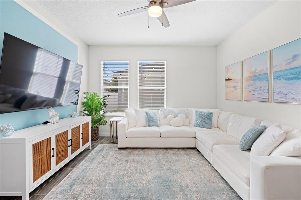 A living room features a white sectional sofa, a television, and a media console — 17167 WRITING ALLEY, WINTER GARDEN, FL