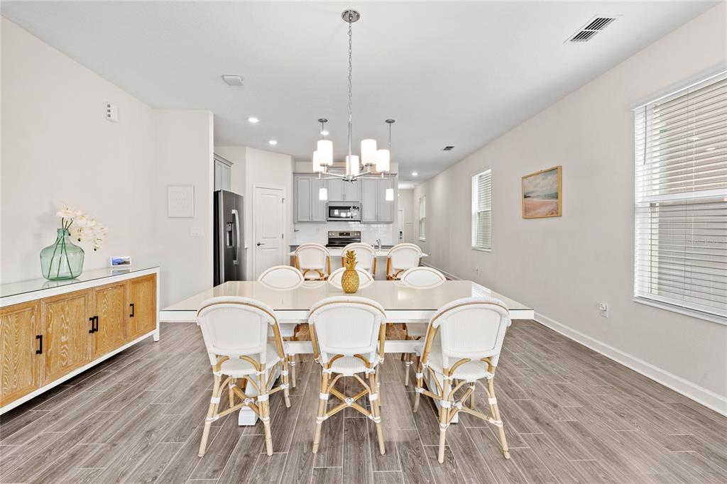 A dining room features a white table with six rattan chairs and a wooden sideboard — 17167 WRITING ALLEY, WINTER GARDEN, FL