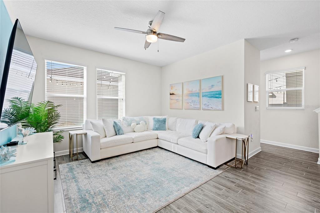 A living room features a white sectional sofa, a blue area rug, and a ceiling fan — 17167 WRITING ALLEY, WINTER GARDEN, FL