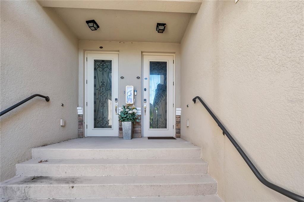 A concrete staircase leads to two white front doors with decorative glass inserts — 5815 WAKE FOREST RUN UNIT 103, LAKEWOOD RANCH, FL