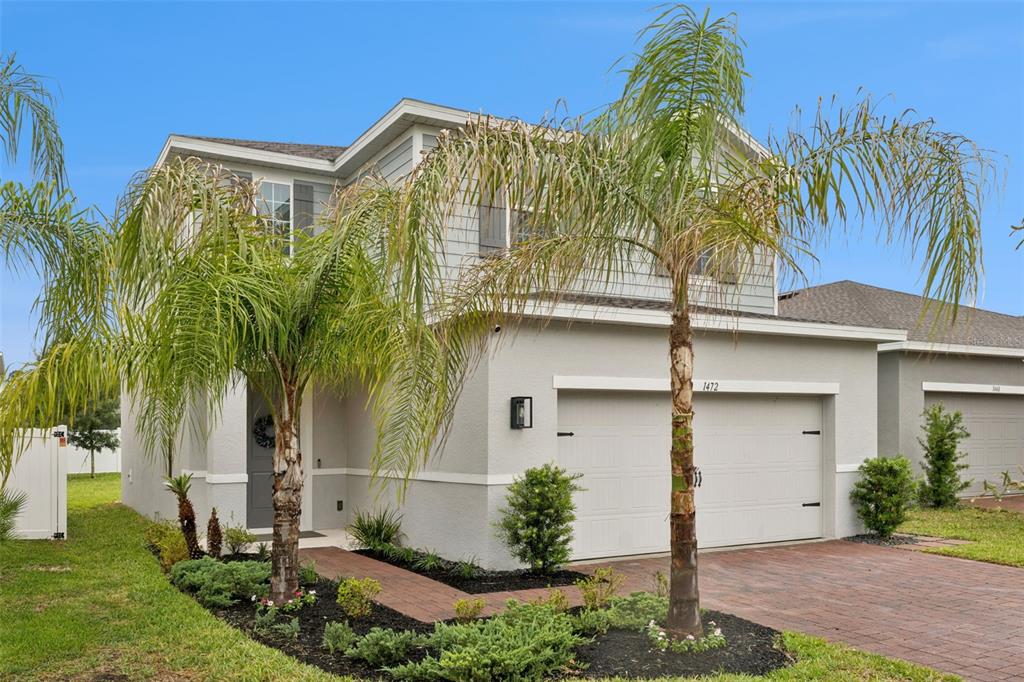 A two-story house with light gray siding, a two-car garage, and palm trees in front — 1472 EUCALYPTUS WAY, DAVENPORT, FL
