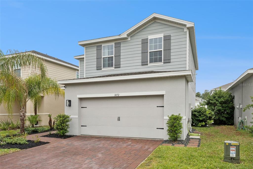 A two-story house with light gray siding, a two-car garage, and a brick paver driveway — 1472 EUCALYPTUS WAY, DAVENPORT, FL