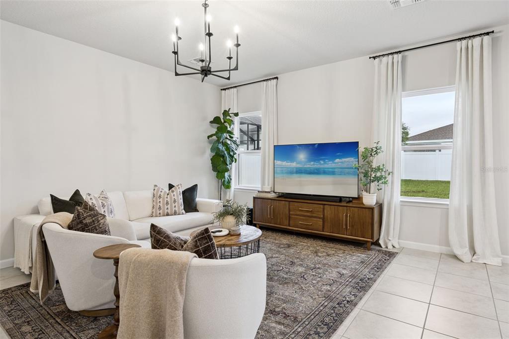 A living room features a white sofa, two armchairs, a wooden media console, and chandelier — 1472 EUCALYPTUS WAY, DAVENPORT, FL