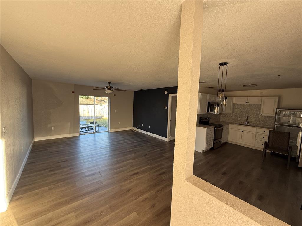An open-concept living area with wood-look flooring leads to a kitchen with white cabinets — 1611 FRUITWOOD DRIVE, LAKELAND, FL