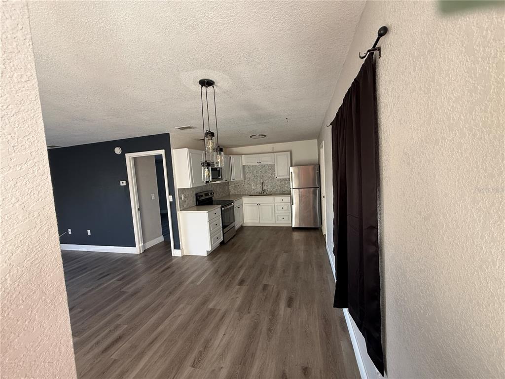 A kitchen with white cabinets and stainless steel appliances opens into a living area — 1611 FRUITWOOD DRIVE, LAKELAND, FL