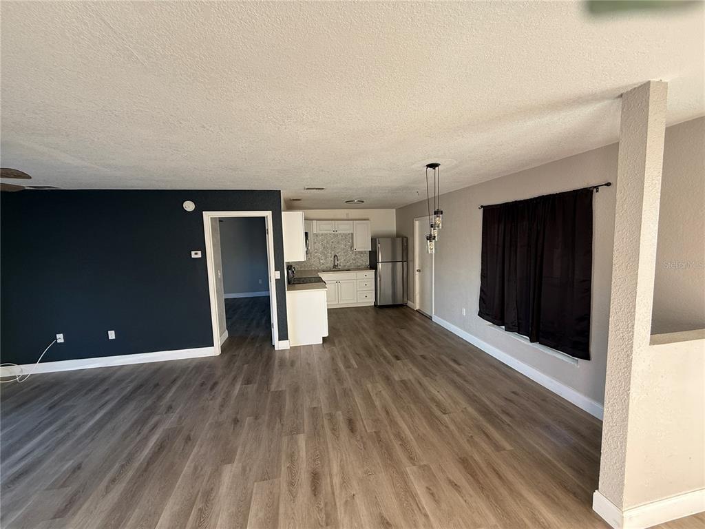 A living room with wood-look flooring leads to a kitchen with white cabinets and appliances — 1611 FRUITWOOD DRIVE, LAKELAND, FL