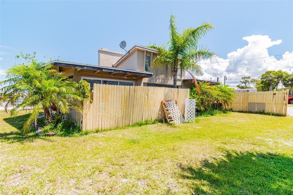 A tan house with a wooden fence and a palm tree in the front yard — 5325 TREADWAY DRIVE, PORT RICHEY, FL