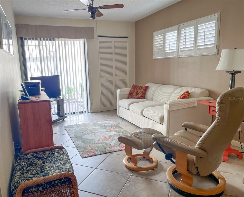A living room features tile floors, a white sofa, a recliner, and sliding glass doors — 690 BIRD BAY CIRCLE UNIT 28, VENICE, FL