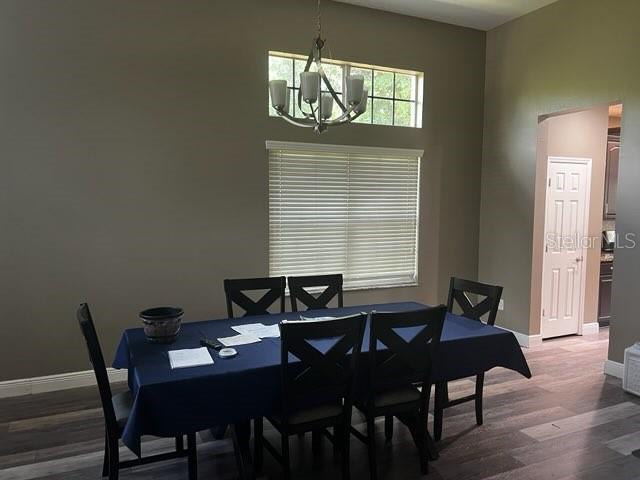A dining room features a dark blue tablecloth, a chandelier, and wood-look flooring — 6528 CARRINGTON SKY DRIVE, APOLLO BEACH, FL