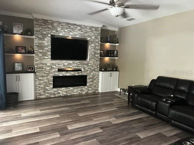 A living room features a stone fireplace wall with built-in shelves and wood-look flooring — 6528 CARRINGTON SKY DRIVE, APOLLO BEACH, FL