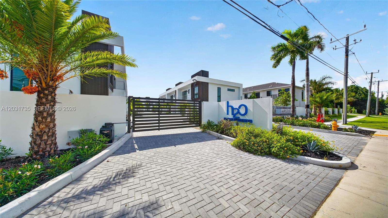 A paved driveway leads to a gated entrance of a modern residential complex with palm trees — 4624 SW 32nd Ave # A3, Dania Beach FL 33312, DANIA BEACH, FL