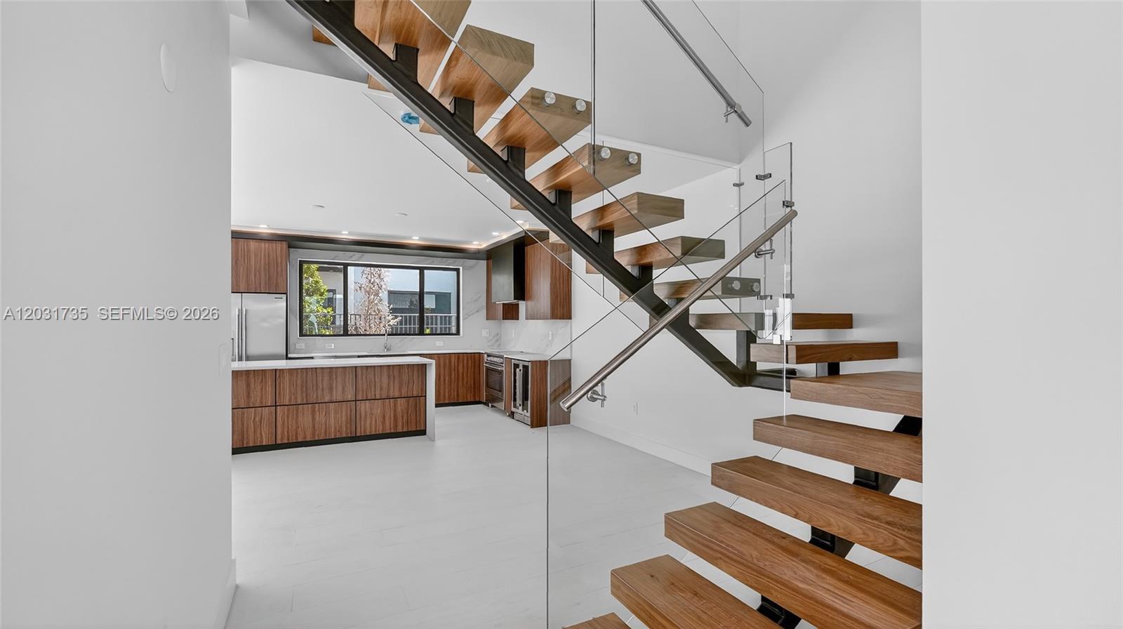 A modern kitchen with wood cabinetry is visible behind a floating wooden staircase — 4624 SW 32nd Ave # A3, Dania Beach FL 33312, DANIA BEACH, FL